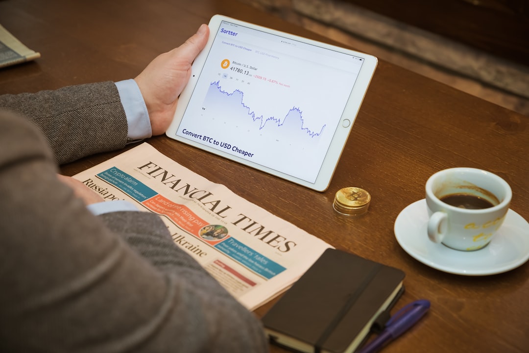 Drinking coffee in a coffee shop checking Bitcoin chart with Financial Times, from United Kingdom, aside.